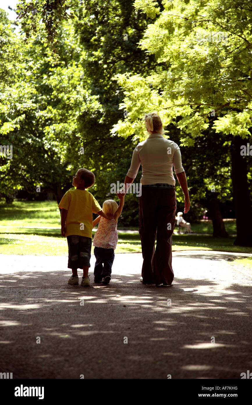 Back view of a young mother walking in the park with two young children Stock Photo