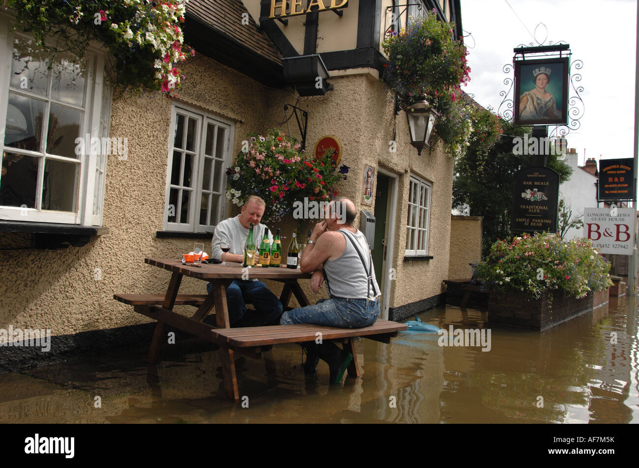 Landlord of the flooded Queens Head pub in Longford Gloucester England July 2007 drinks wine at