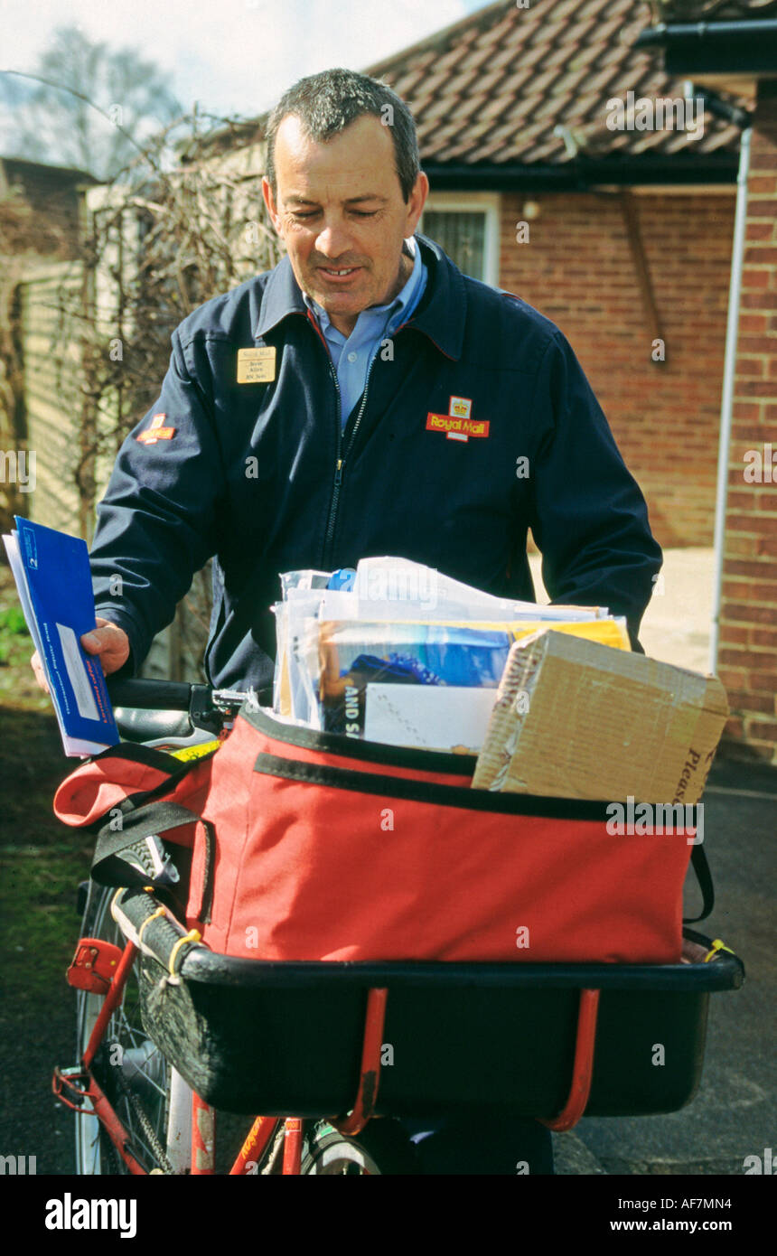 postman on his round delivering letters and parcels loaded onto bicycle Stock Photo