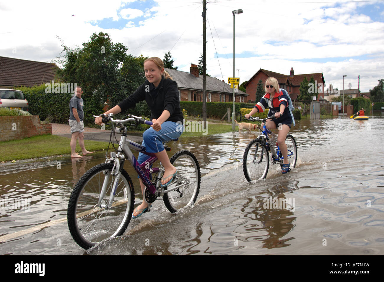 Two women cycling through floods in the Longford area of Gloucester England July 2007 after severe flooding Stock Photo