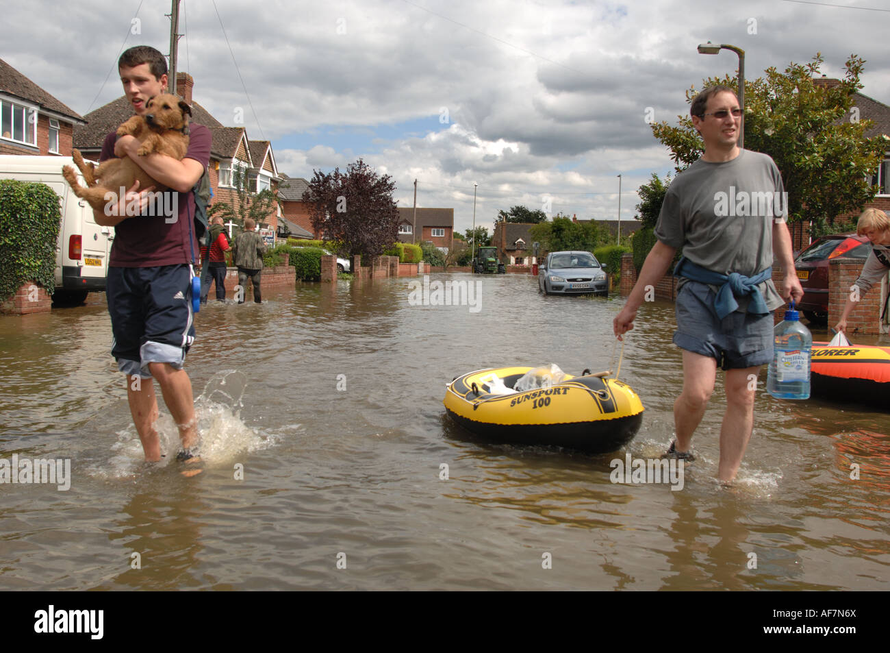 People with small boats carry drinking water and a dog through floods in the Longford area of Gloucester England July 2007 Stock Photo