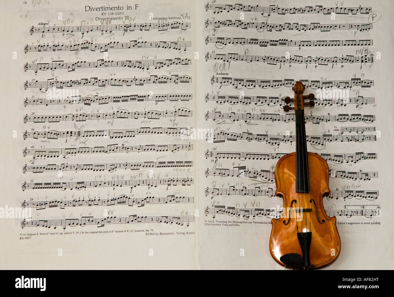 Still life: 1 miniature violin placed on a score (Divertimento in F major, K.138 / 125c (Mozart, Wolfgang Amadeus)) open, annotated in pencil. Stock Photo