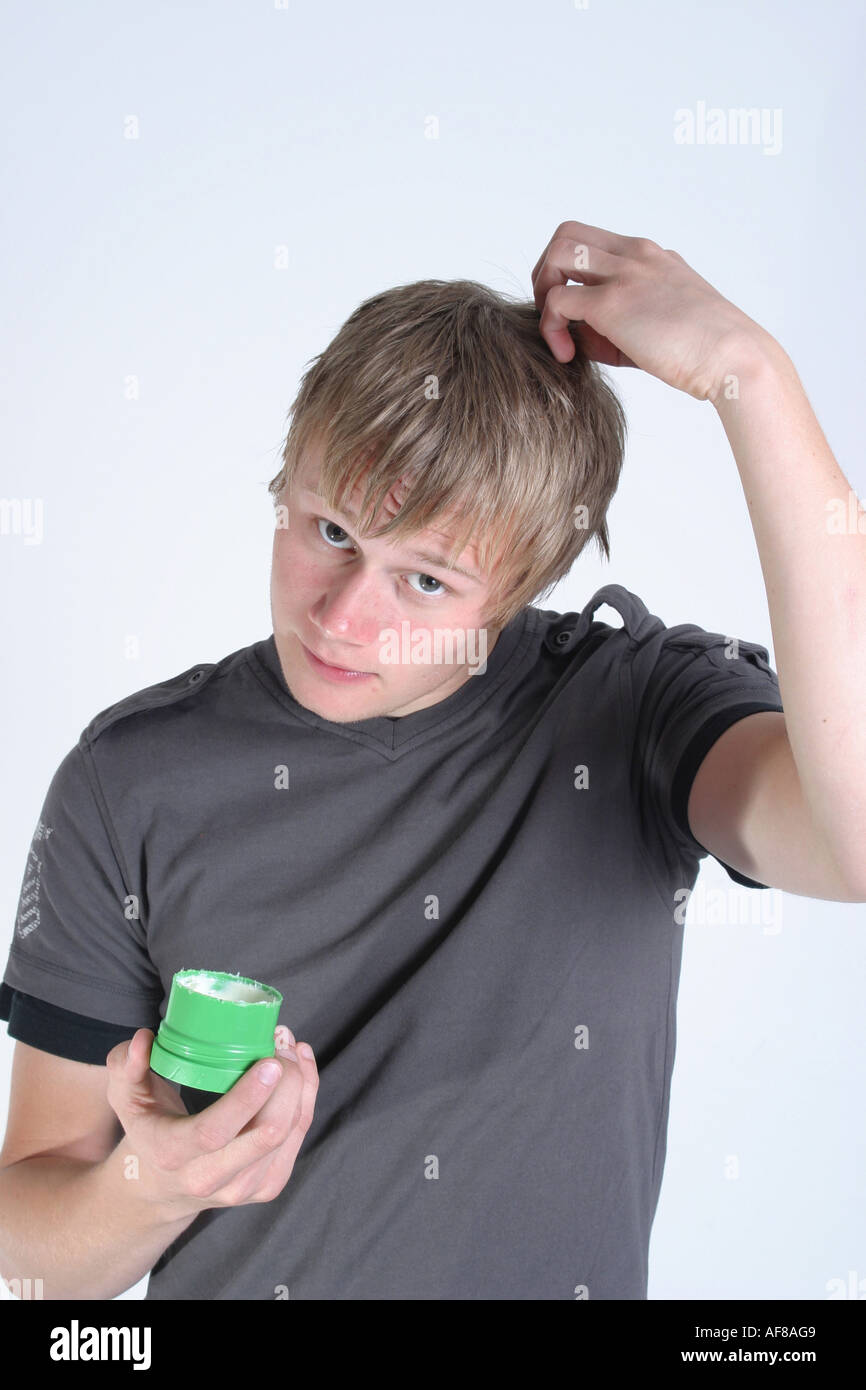 A Stock Photograph of a Young Adult using Wax to Style his Hair Stock