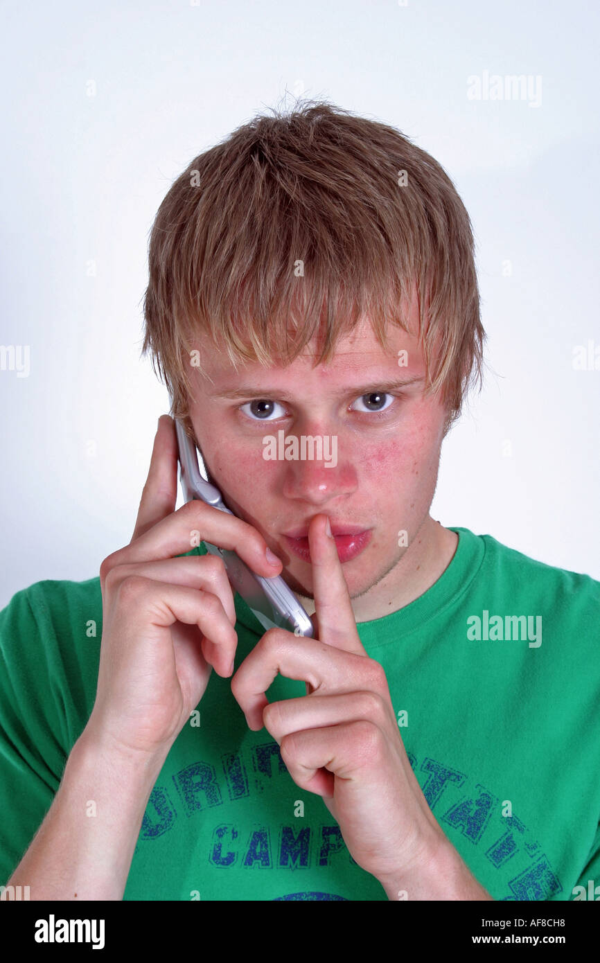 A Stock Photograph of a man on his Mobile Phone With Finger Sign Saying be Quiet Stock Photo