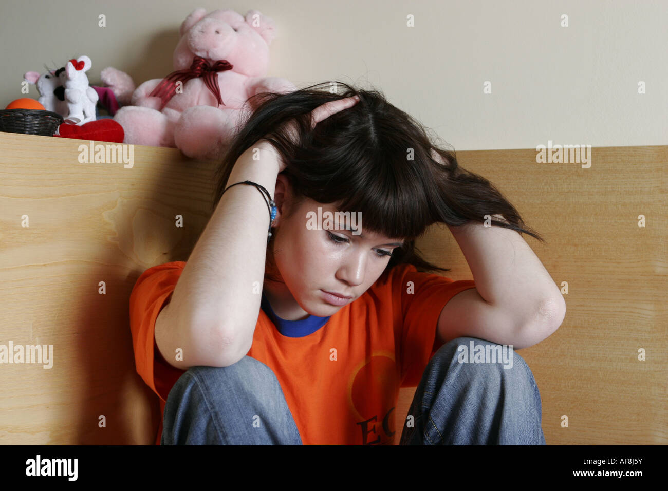 Sad teenager girl sitting on the bed Stock Photo