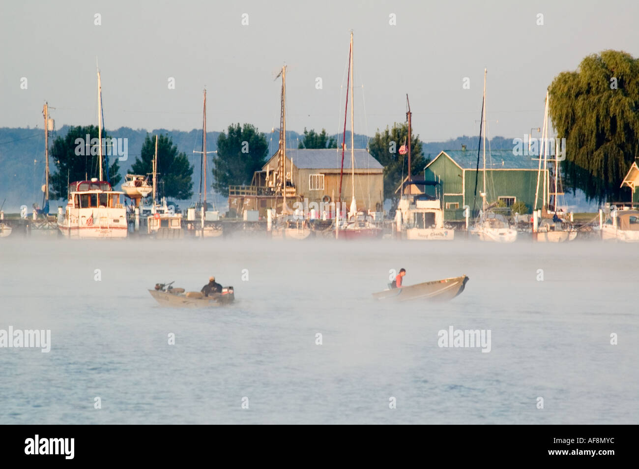Two small fishing boats pass in front of a marina on White Lake near Montague MI Stock Photo