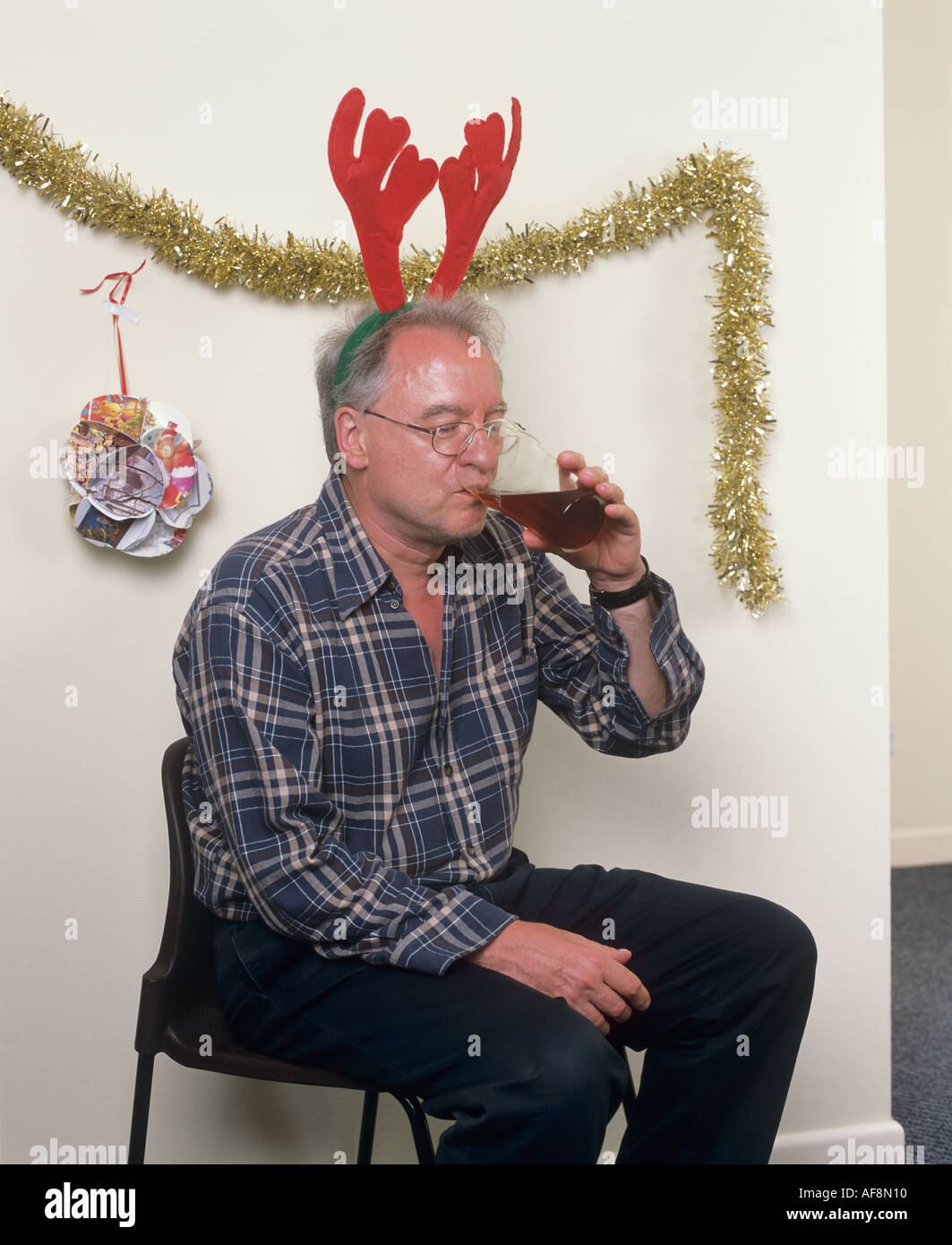 Man alone at Christmas party wearing antlers Stock Photo
