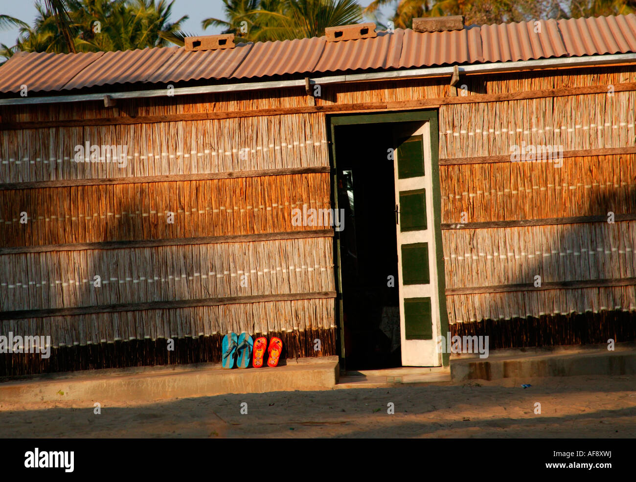A traditional reed hut with two slops outside the door in a village in ...