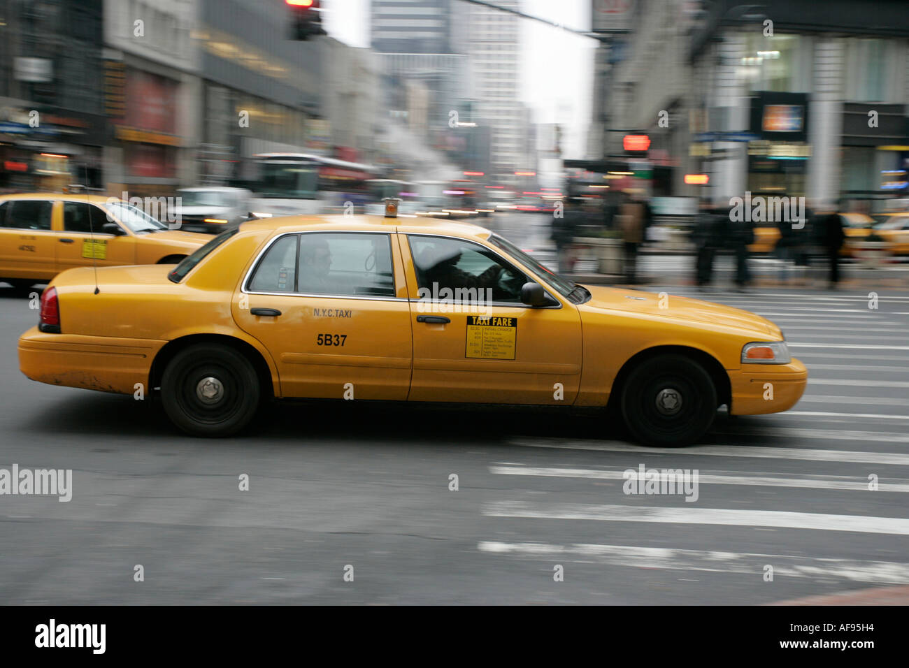 yellow cab blurring past crosswalk and pedestrians new york city new york USA Stock Photo