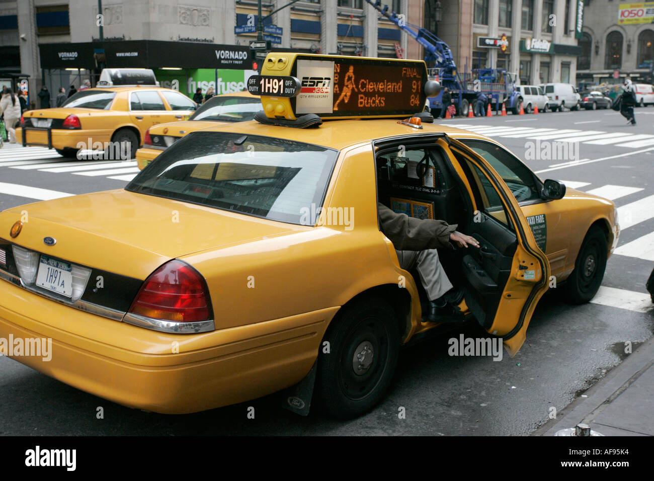 white caucasian passenger closes rear door of yellow cab on taxi rank at crosswalk on 7th Avenue outside Madison Square Garden Stock Photo