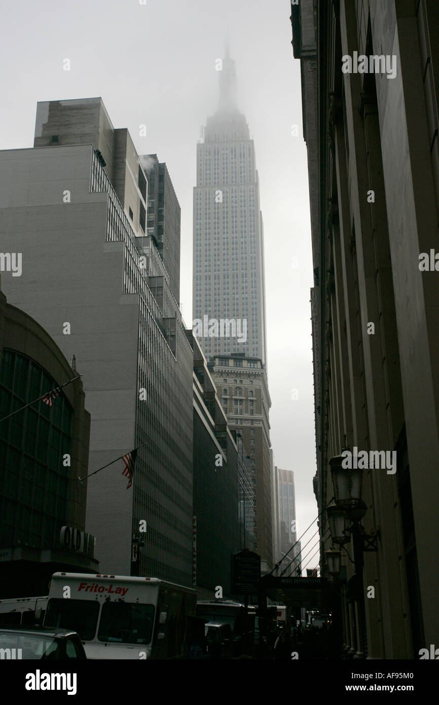 empire state building shrouded in mist in amongst dark cold buildings on 33rd Street new york city new york USA Stock Photo