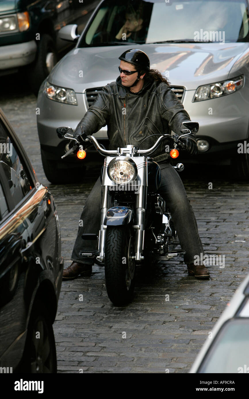 cool biker in leather jacket sits on new motorcycle in traffic on cobbled streets lower manhattan Stock Photo