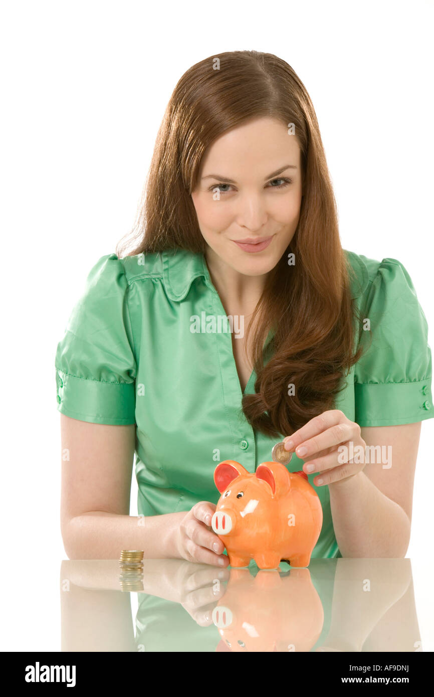 Young woman putting coin into piggy bank, close-up Stock Photo - Alamy