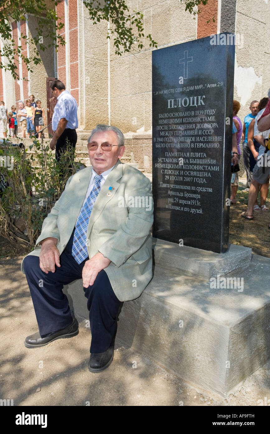 Dr. Edwin Kelm sitting at the memorial stone recalling the foundation of the village of Plotzk / Ukraine by German colonists Stock Photo