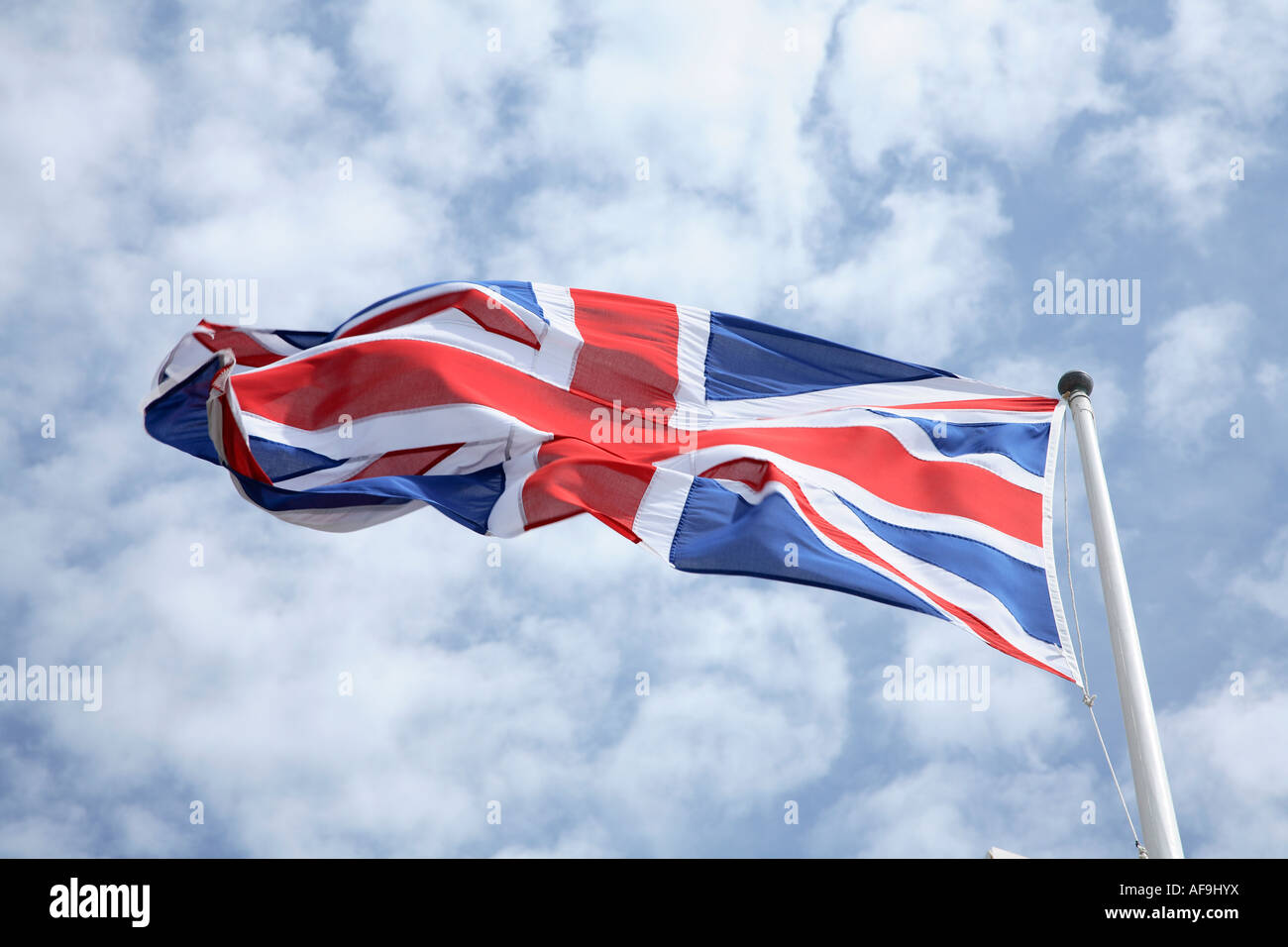 The Union Jack flag blowing in the wind with a blue sky and clouds in ...