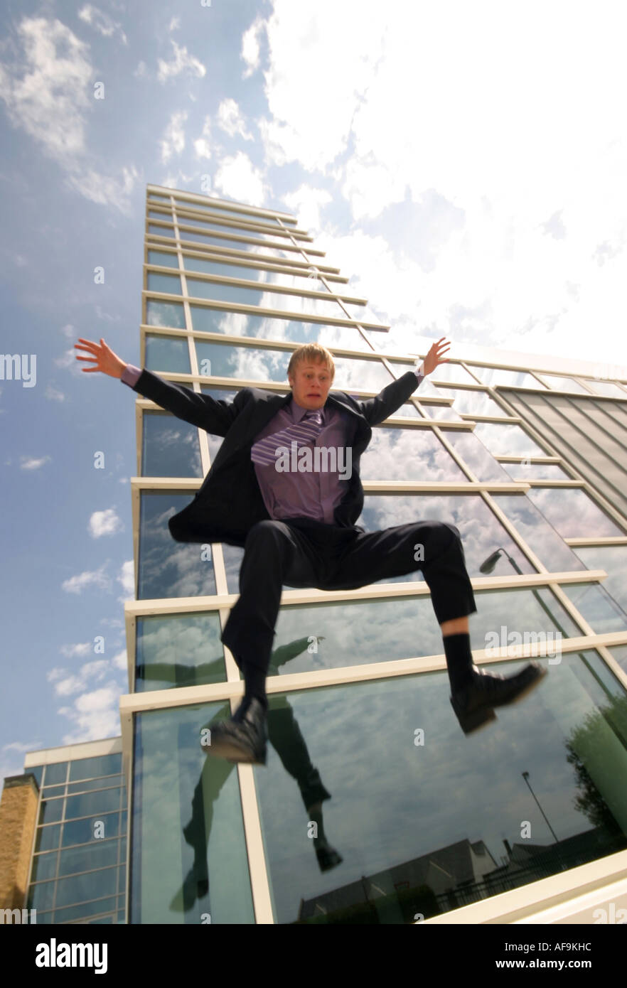 A Stock Photograph of a Young Adult Businessman Jumping from the Top of a Modern Office Block Stock Photo
