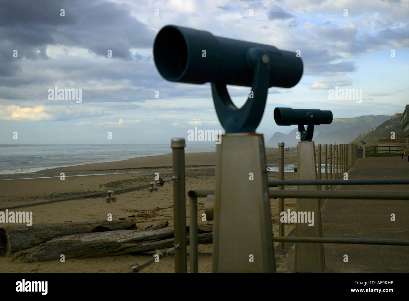 Viewing telescopes or spy scopes at a coastal park in California over a sandy beach beneath a cloudy sky in the evening Stock Photo