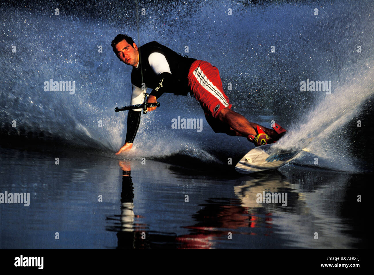 Water-skier on a wakeboard dragging his hand on the surface of the water while executing a turn South Africa Stock Photo
