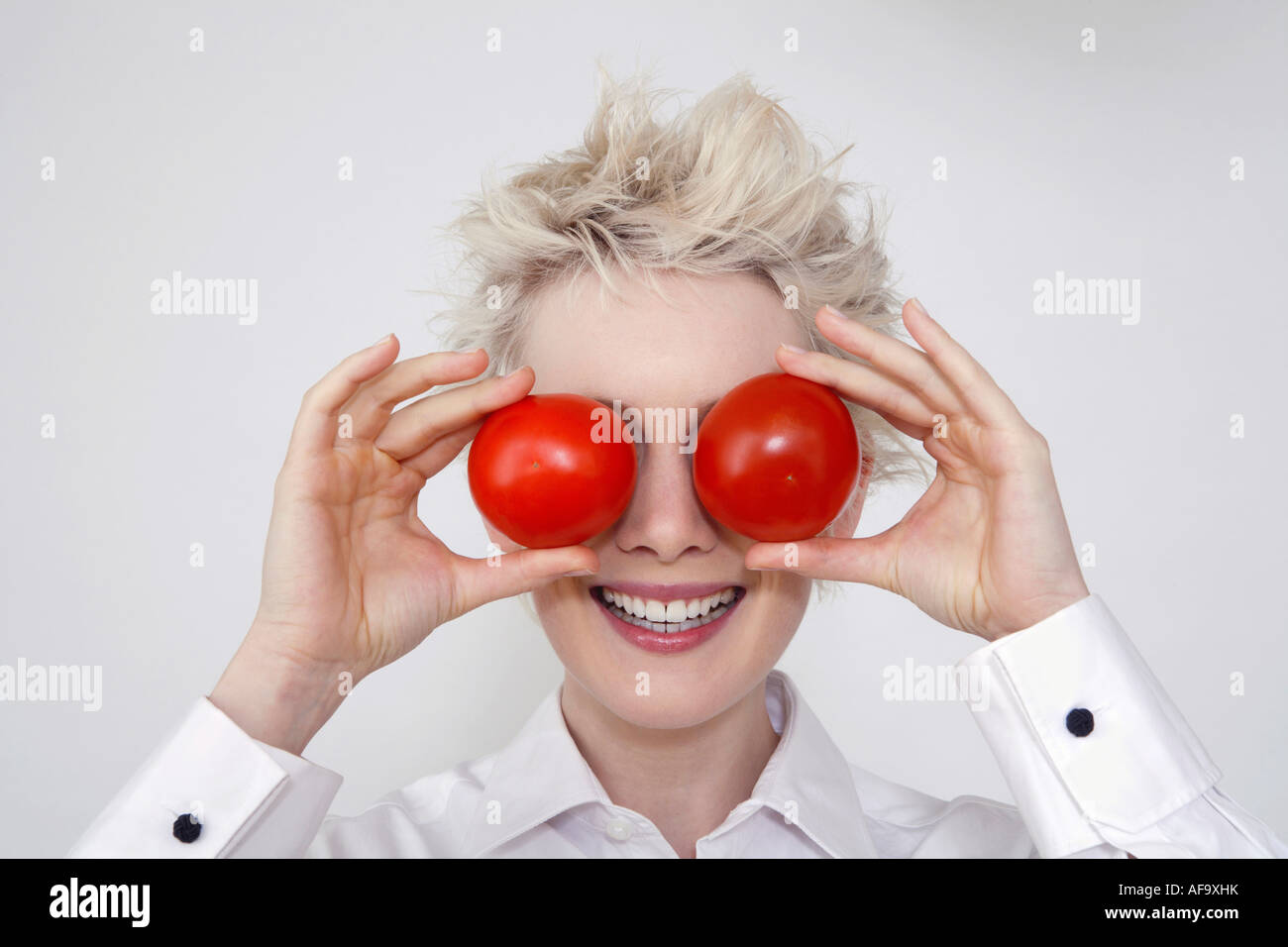 Young woman holding tomatoes in front of her eyes, portrait Stock Photo ...