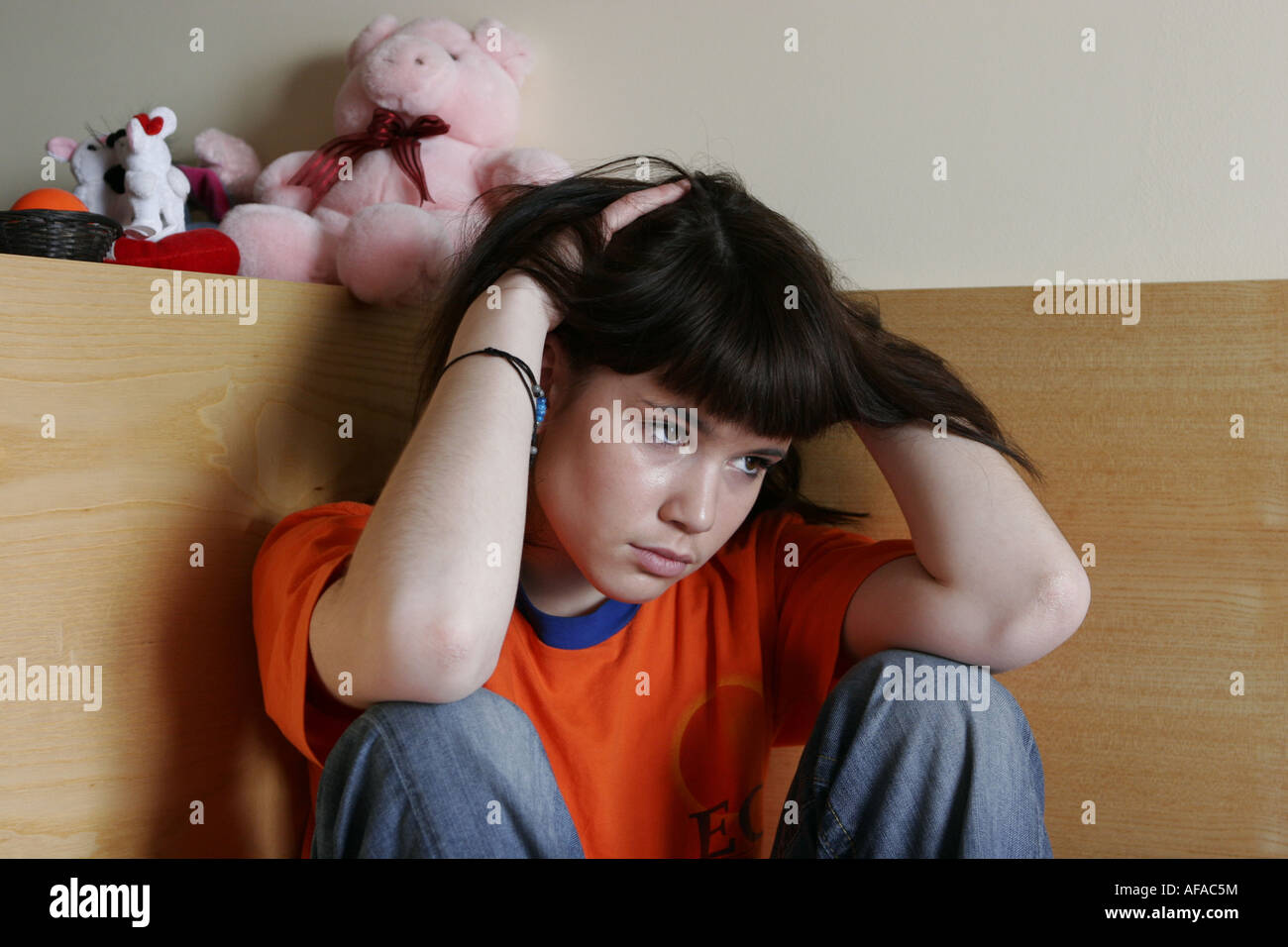 Sad teenager girl sitting on the bed Stock Photo