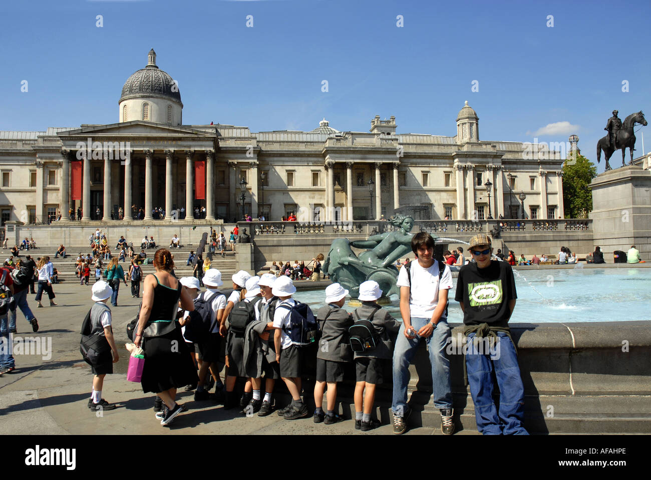 Tourists enjoying Trafalgar Square, bordered by The National Gallery and St Martin in the Fields Church. London England. Uk 2006 Stock Photo