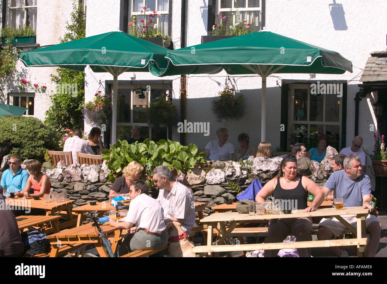 tourists drinking outside the Royal Oak pub in ambleside Lake district during fine summer weather UK Stock Photo