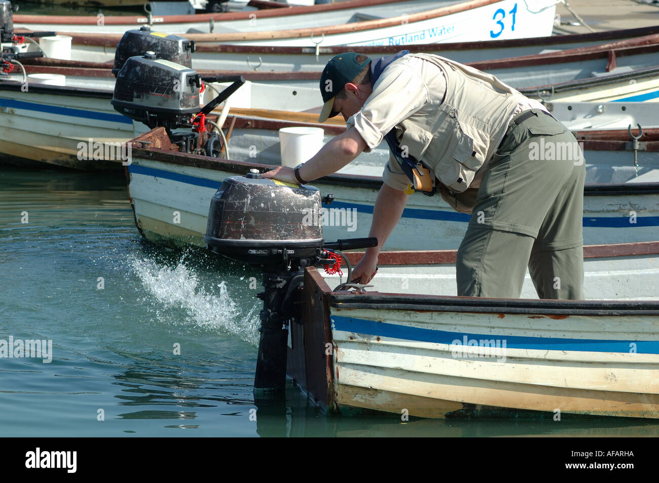 man starting outboard motor on fishing boat on Rutland Water, England