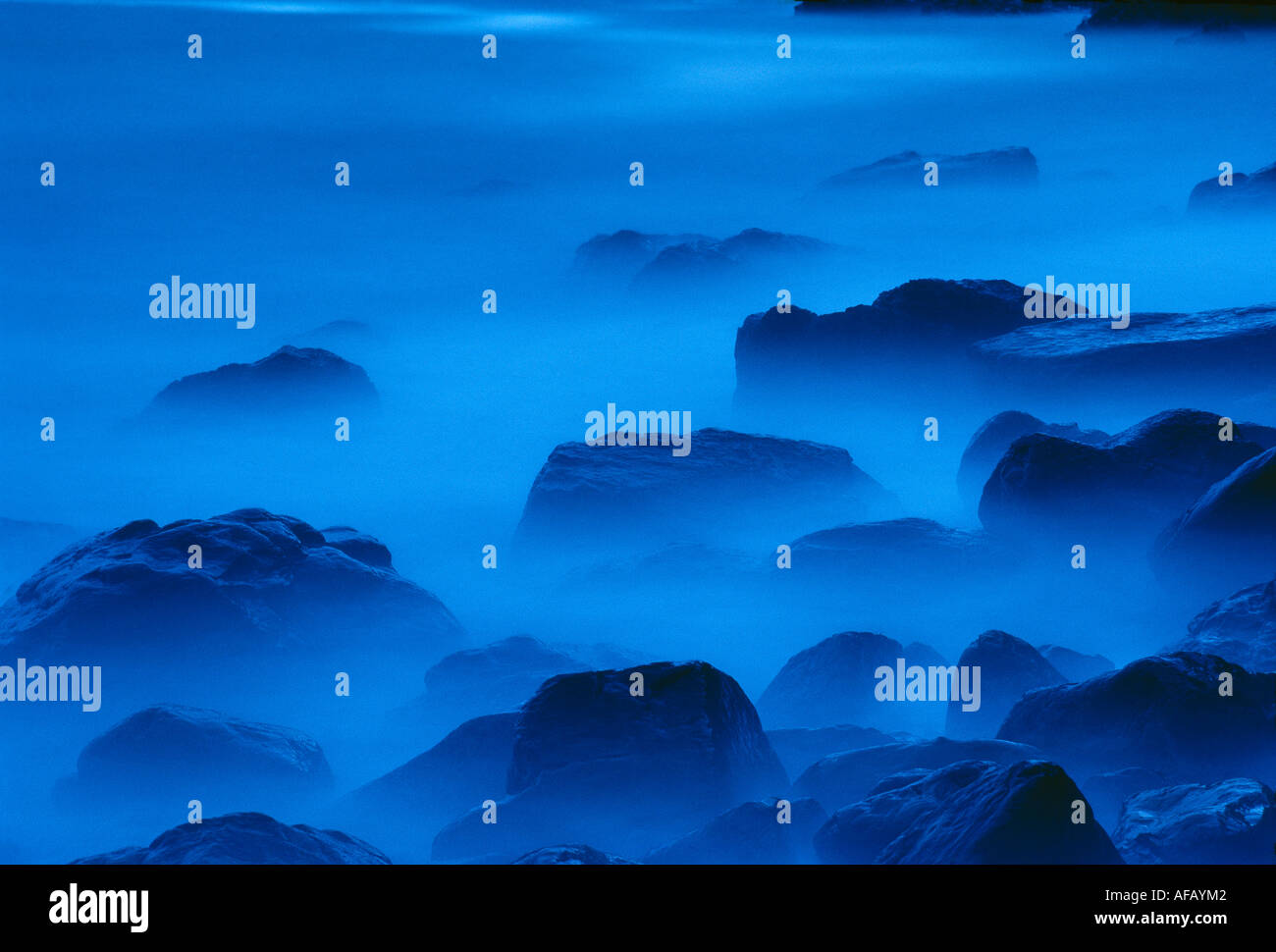 abstract detail of waves breaking around rocks at twilight Caerfai Pembrokeshire Wales UK Stock Photo
