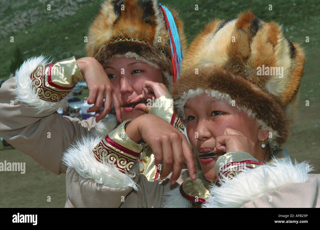 Portrait of young girls playing national Altaic instrument komus. El-Oiyn - national festival of Altaic people. Russia Stock Photo