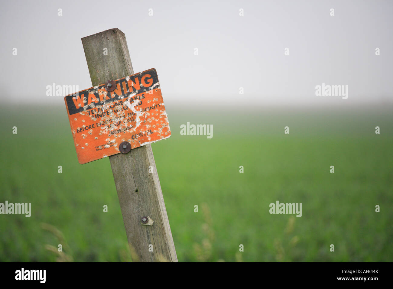 telephone cable underground warning sign with multiple bullet holes in it northern illinois countryside Stock Photo