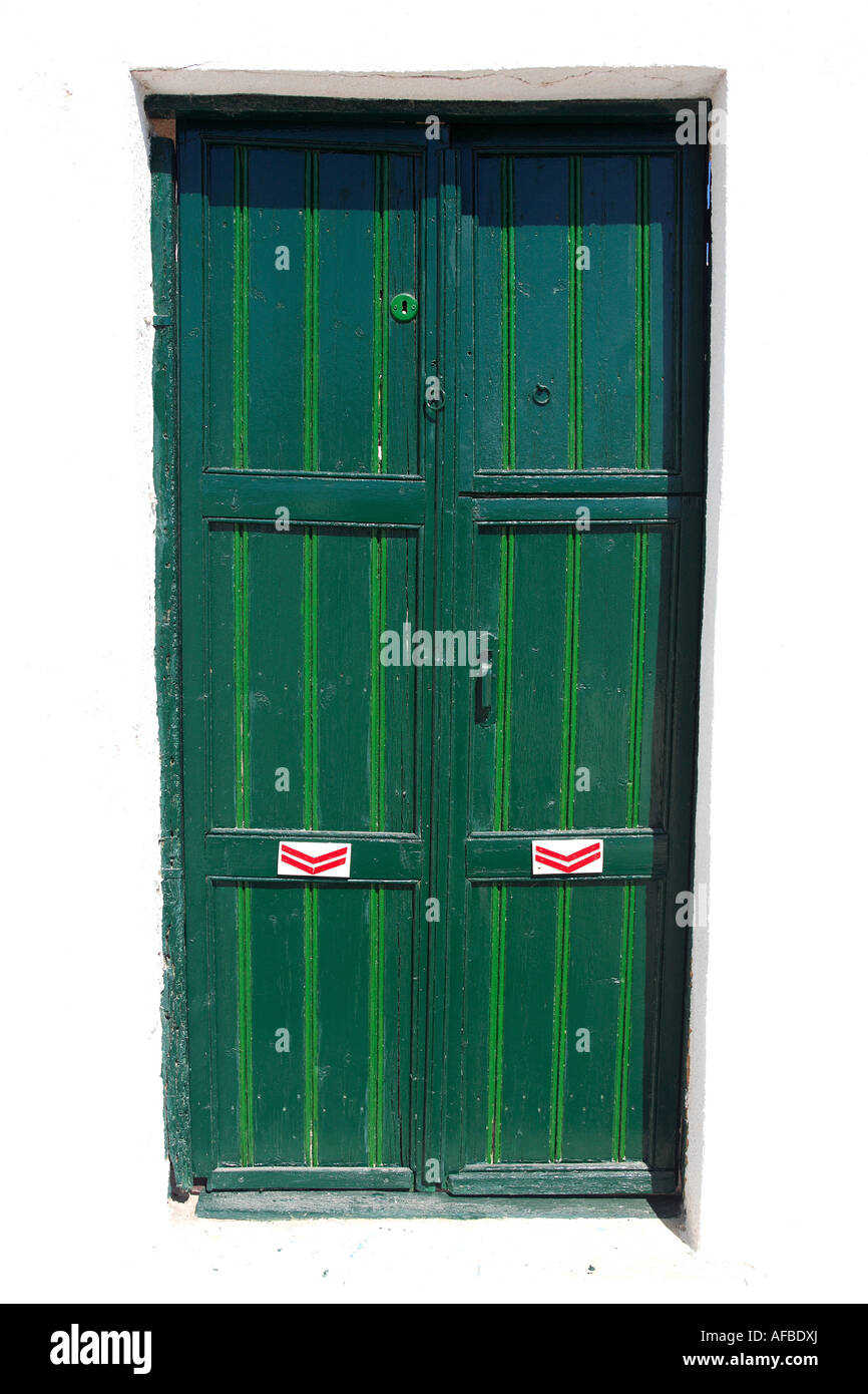 green painted double doors in whitewashed wall Stock Photo