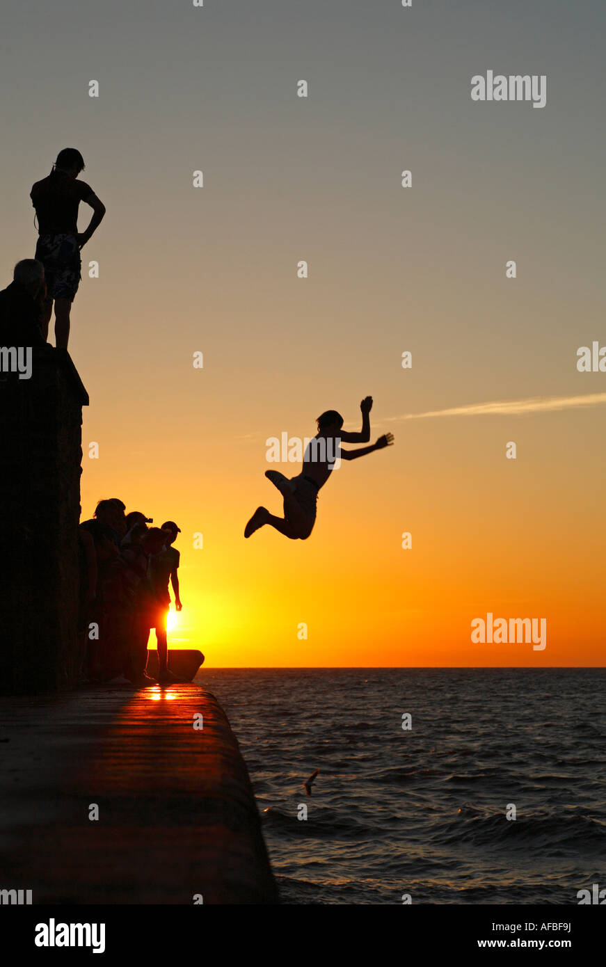 Young man tombstoning - jumping into the sea from a height. Stock Photo