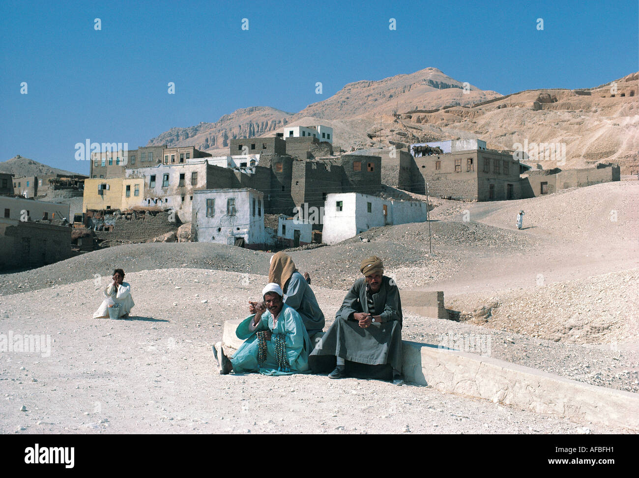 Villagers in traditional dress outside their village of painted Arab style houses near the Valley of the Kings Egypt Stock Photo