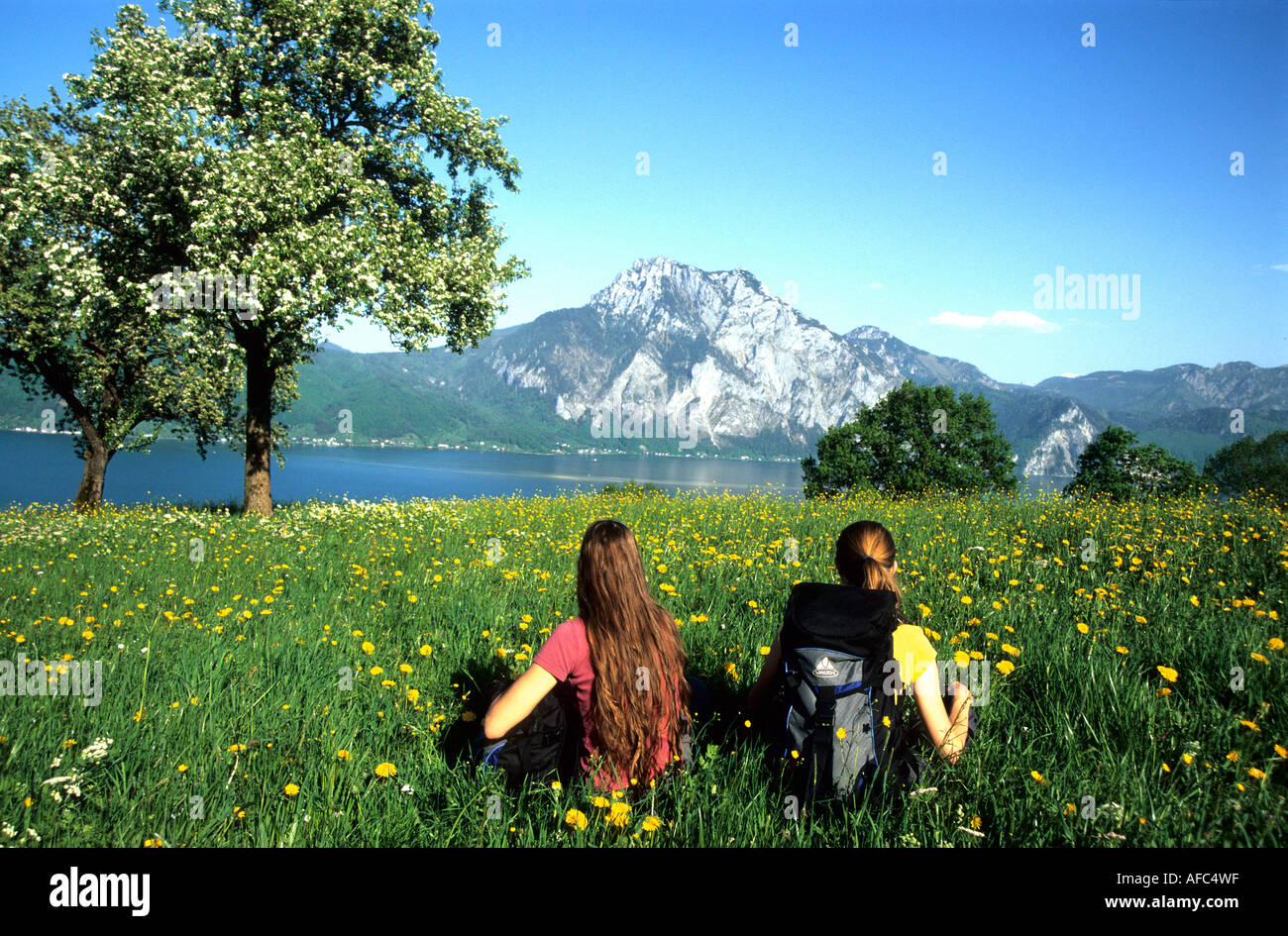 Girls Hiking, Traun Lake, Two girls have a hiking break on Traun Lake, Salzkammergut, Austria, Rast auf Fruehlingswiese vor Trau Stock Photo
