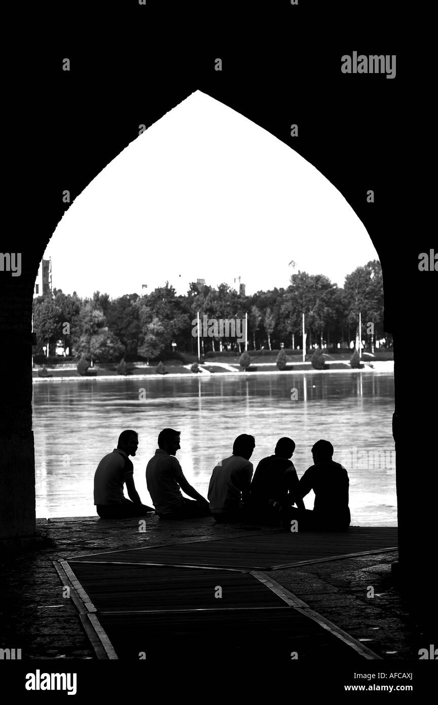 Group of friends sitting under arch on Khaju Bridge in Isfahan, Iran Stock Photo