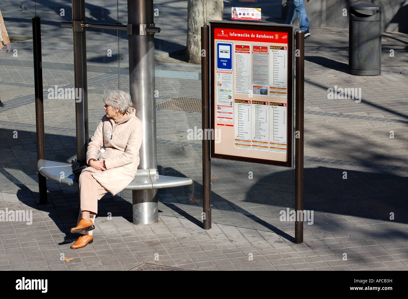 Lady waiting at bus stop, Madrid Stock Photo