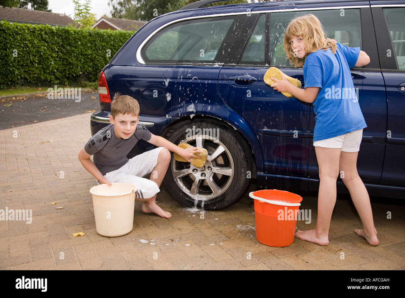 Boy and girl washing car for pocket money Stock Photo