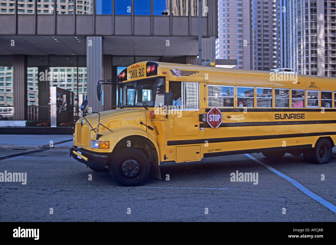 A traditional yellow school bus on its route through the streets and bridges of downtown Chicago Stock Photo