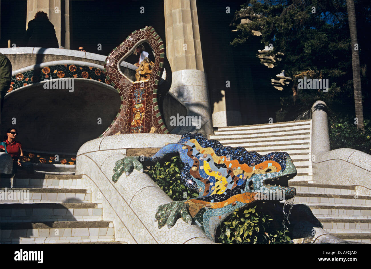 In Park Güell created by Antoni Gaudí a salamander adorns the stairway to a pillared hall and plaza Stock Photo