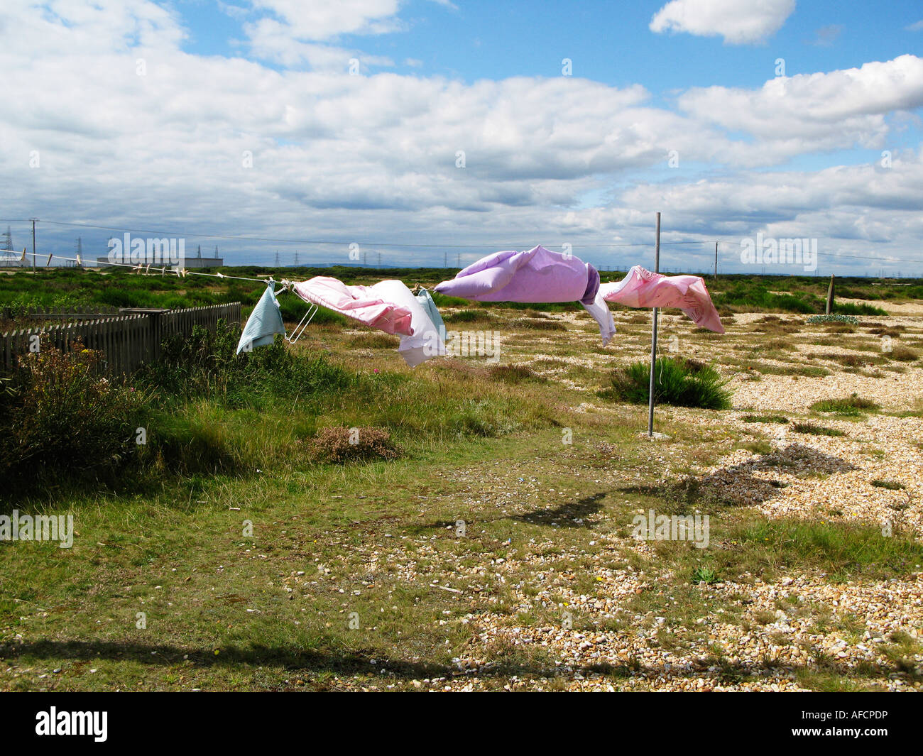 A washing line with colourful sheets flapping in the wind on the shore at Dungeness Kent Stock Photo