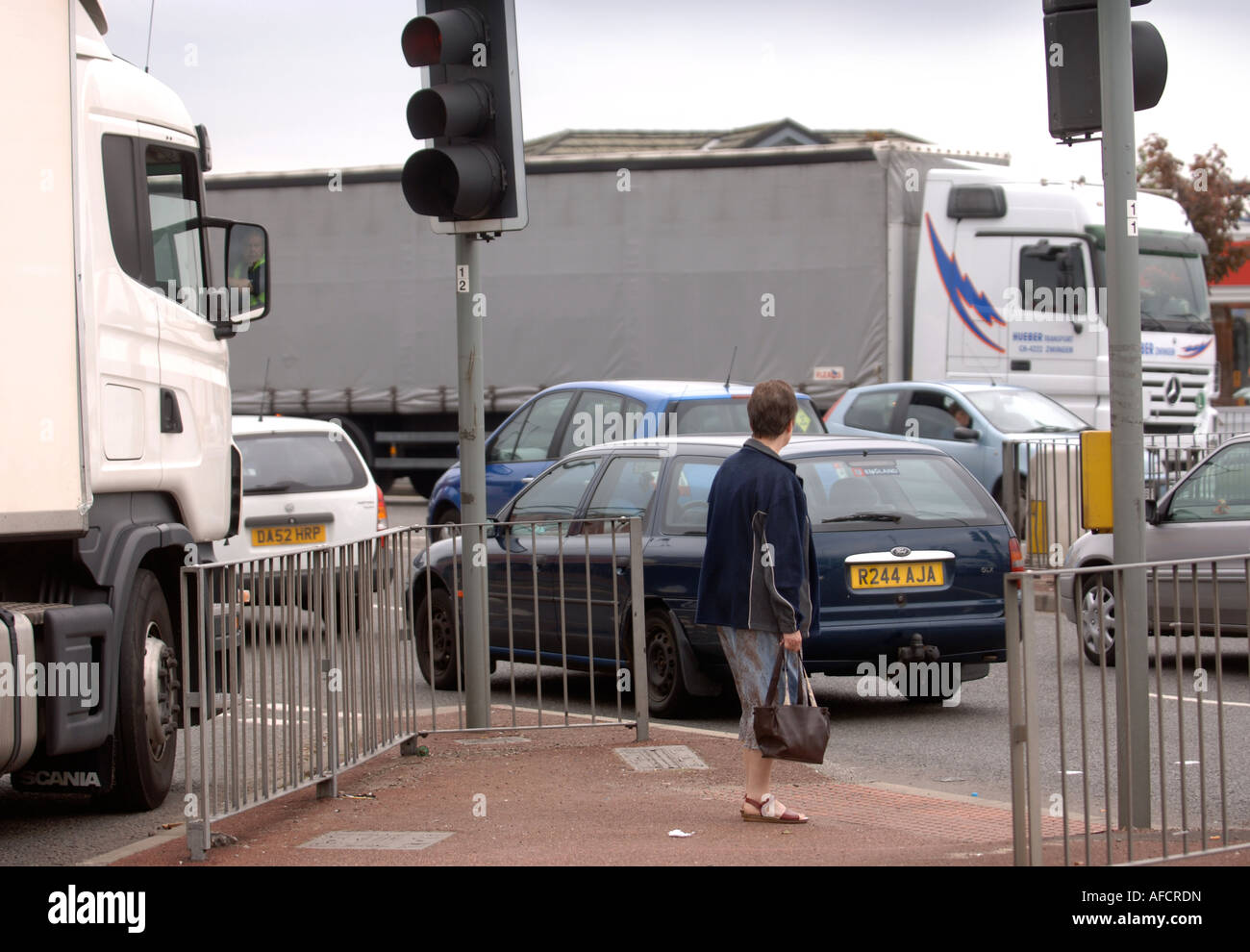 A WOMAN WAITING AT A PEDESTRIAN CROSSING AT A ROAD JUNCTION IN BURY UK ...