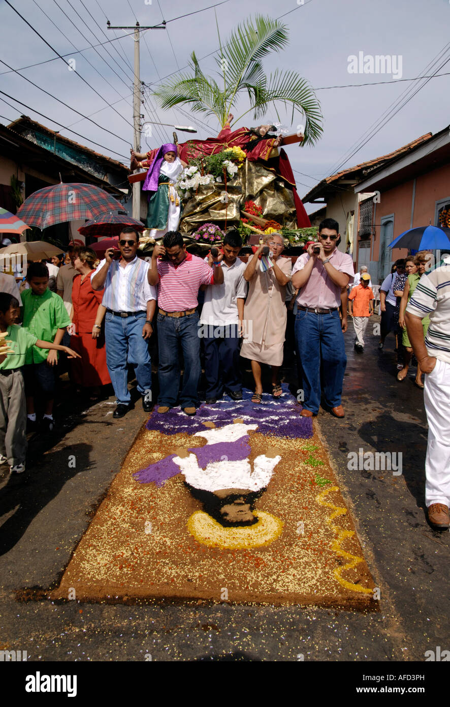 Devotees carry a model of the crucifiction over a sawdust carpet alfombra during a Semana Santa procession, Leon, Nicaragua Stock Photo