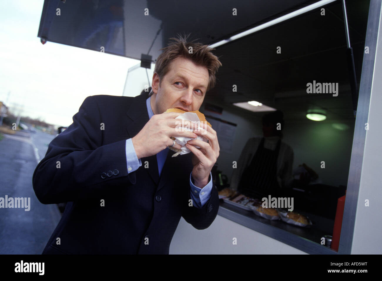 man eating a hamburger on the move Stock Photo
