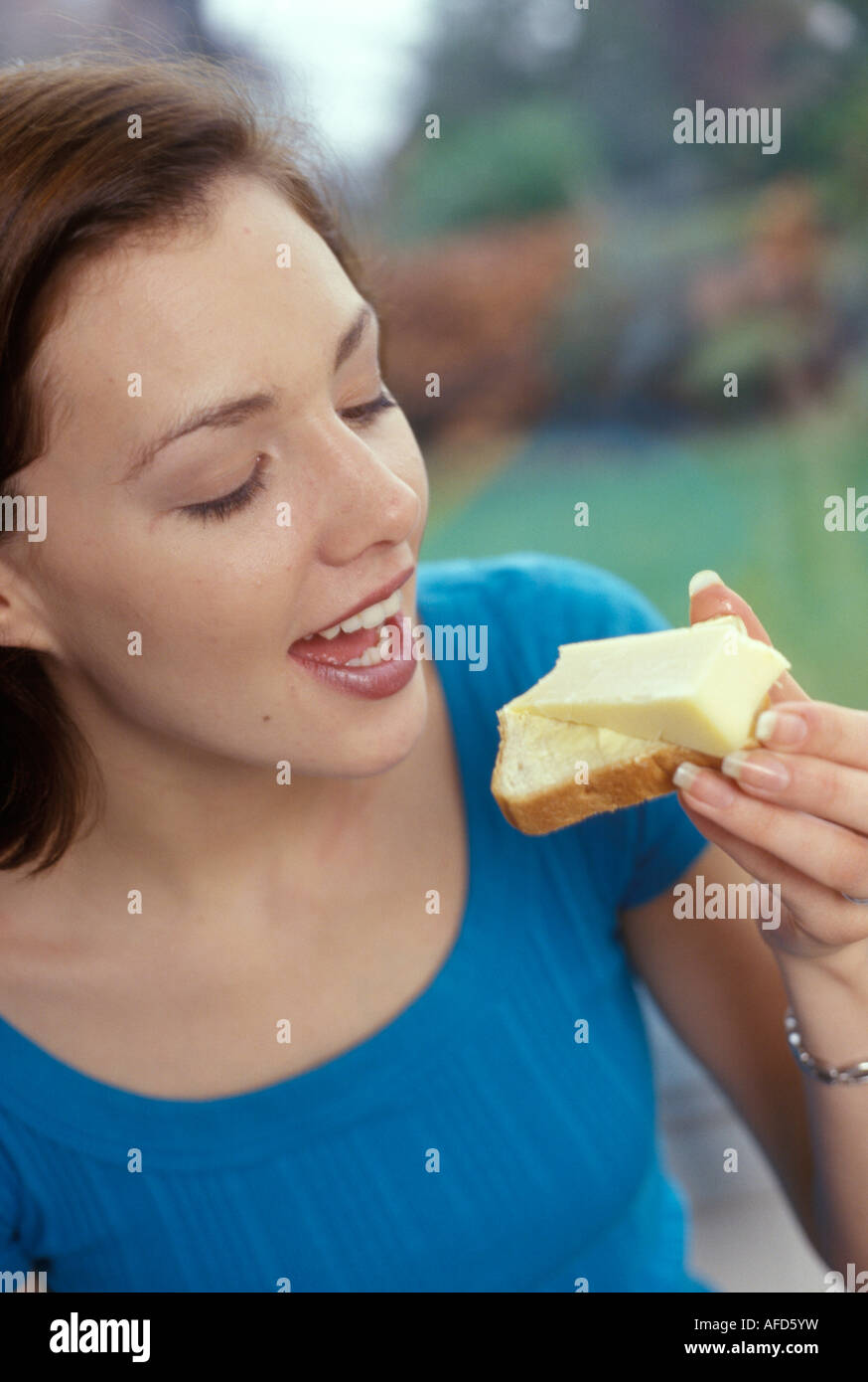 woman eating a piece of bread and cheese Stock Photo