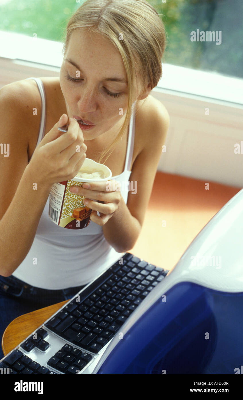 woman at a computer eating a tub of ice cream Stock Photo