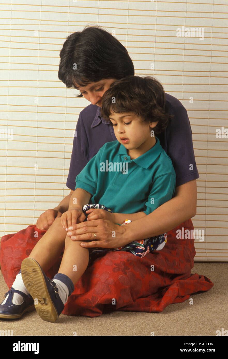 mother rubbing her child s bruised knee better Stock Photo Alamy