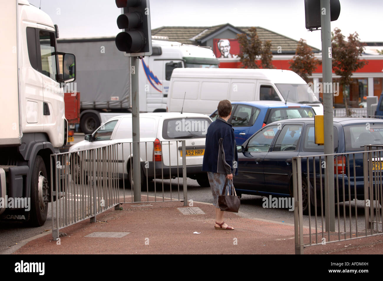A WOMAN WAITING AT A PEDESTRIAN CROSSING AT A ROAD JUNCTION IN BURY UK Stock Photo