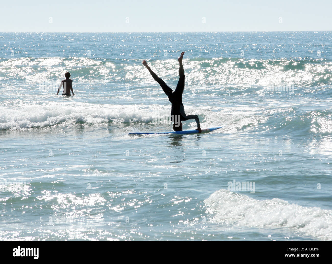 A surfer stands on his head on his board while surfing Stock Photo Alamy