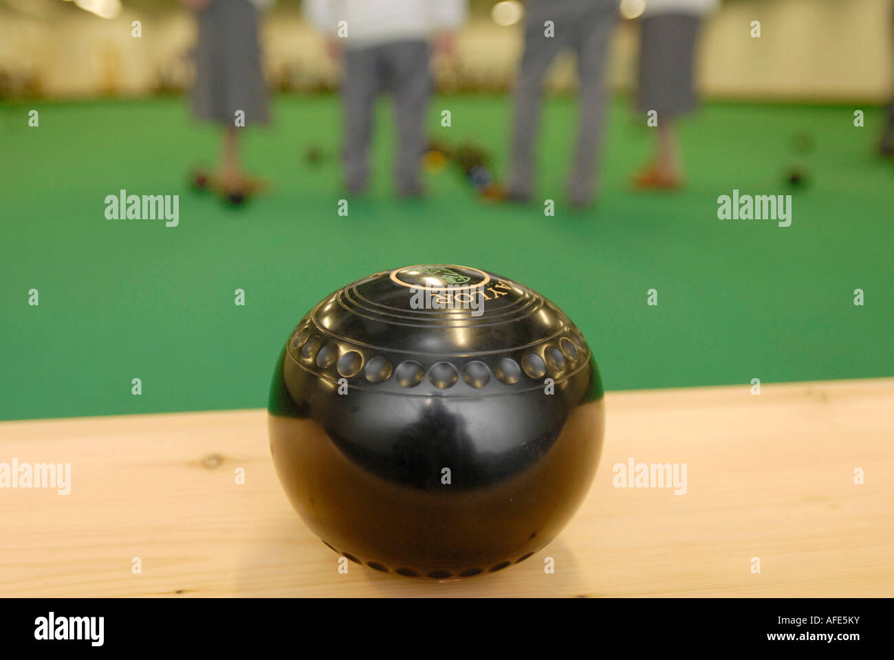 Bowling ball with bowlers at an indoor bowls green Stock Photo