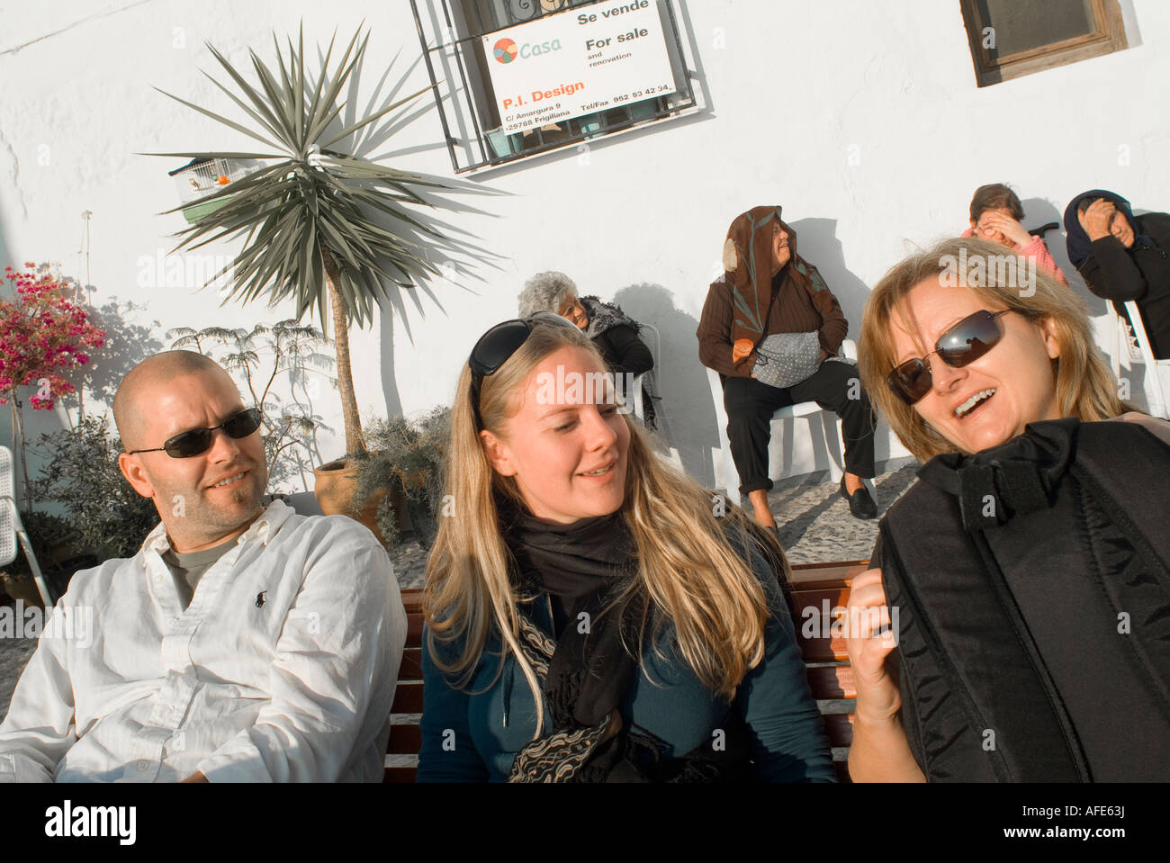 Contrasting cultures Spanish and American different generations travelers and locals sitting outside in separate groups Stock Photo